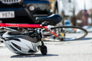 Close-up of a bicycling helmet fallen on the asphalt next to a bicycle after car accident on the street in the city of Johns Creek, GA