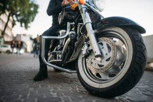Biker in leather clothes poses on a motorcycle, front view from ground, classical chopper. Vintage bike, freedom lifestyle, biking