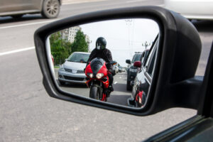 a motorcycle rider in the rear view mirror of a car in Alpharetta, GA